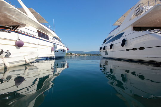 reflections of super yachts and motor power boats in a marina	