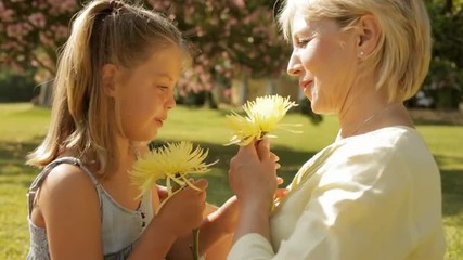 grandmother and granddaughter playing with flower in park - Powered by Adobe