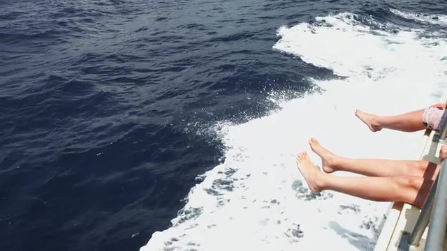 Two people on a yacht enjoy waves of the sea