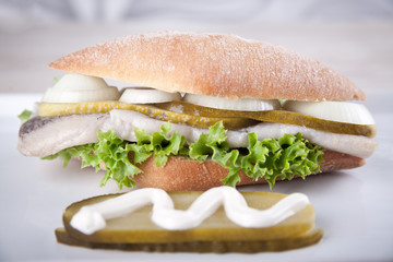 Frisches Fischbrötchen mit Salat, sauren Gurken und Zwiebeln