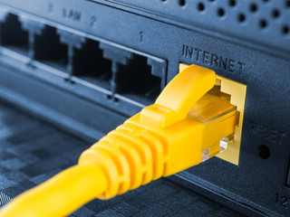 Yellow network cable connected to a router or modem - obrazy, fototapety, plakaty