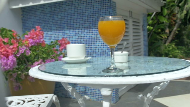 Table with coffee and orange juice, outdoor terrace.