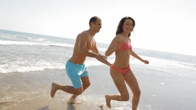young couple running and chasing on the beach