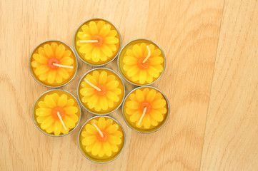 Seven sunflower candles align in hexagonal on the wood backgroun