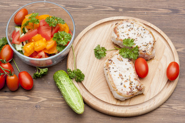 Fried pork steak with vegetables and parsley on a wooden board