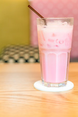 Cold pink milk in glass  on wood table