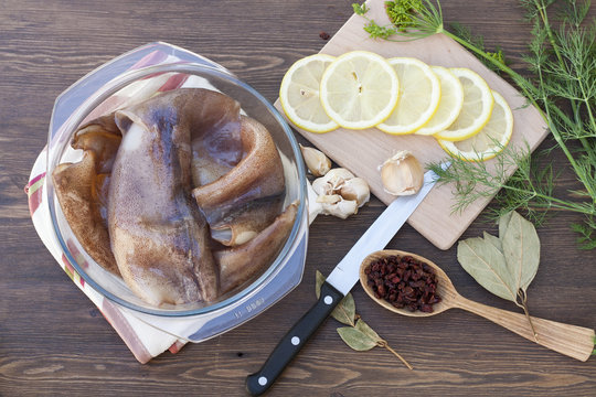 Fresh squid carcass in a glass pot with herbs and sliced lemon