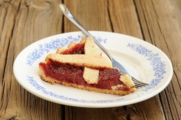 Piece of lattice flan with strawberry jam cut with metal fork on