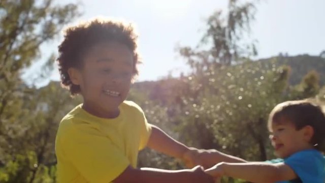 Slow motion of two children twirling in park.