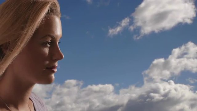 Woman's face with clouds in the background. 