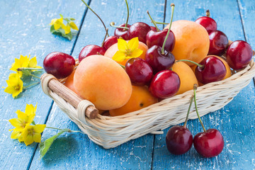 Basket with cherries and apricots berries, flowers loosestrife