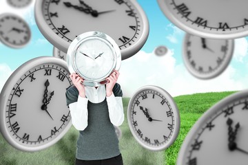 Composite image of woman holding clock in front of her head 