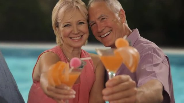zoom in shot of senior couple relaxing by poolside with drinks
