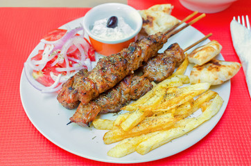 greek souvlaki with fries and cream cheese on a table in a restaurant