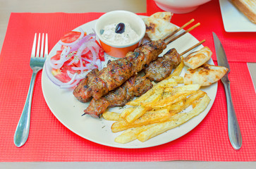 greek souvlaki with fries and cream cheese on a table in a restaurant
