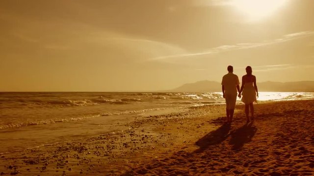 young couple walking on beach in sunset