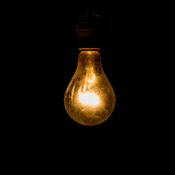 Old light bulb glowing in dark.
