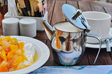 Metal coffee pot with cappuccino and fruit yogurt