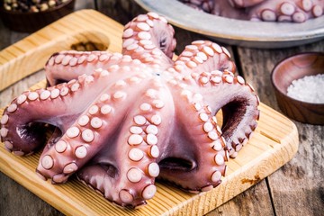 whole fresh raw octopus  on cutting board with sea salt © NBLX