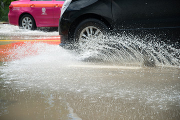 Car's wheels ride on water splashing on the road