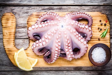 whole fresh raw octopus with sea salt and lemon on cutting board © Ekaterina Kondratova