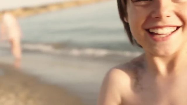Slow motion of boy twirling around on beach.
