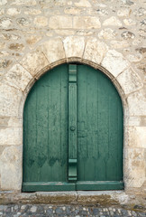 Puerta verde en arco de casa de piedra antigua