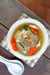 Minced pork wrapped in cabbage soup on wood table.