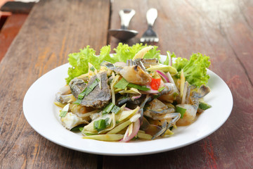 spicy mango salad with blue crab on wood table.