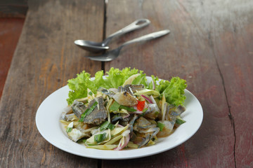 spicy mango salad with blue crab on wood table.