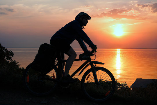 Silhouette of a cyclist in the rays of the setting sun