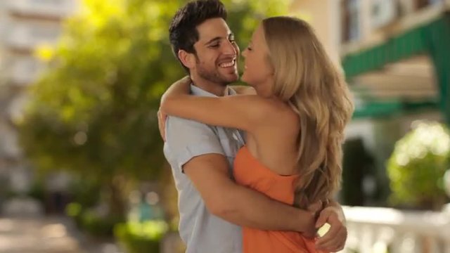 young couple hugging and twirling in park