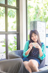 Happy asian young woman drinking coffee