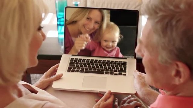 Senior couple enjoying video online with daughter and grandchild.