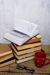 vintage books, notebook, pen, glasses and mug on wooden background