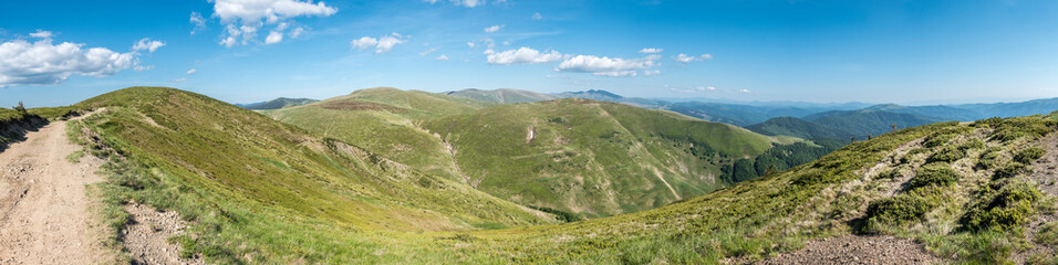Fototapeta na wymiar Spring mountains under blue sky with clouds - panoramic view