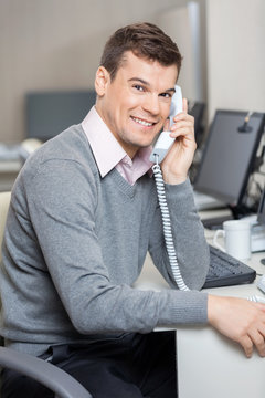 Male Customer Service Representative Using Telephone At Desk