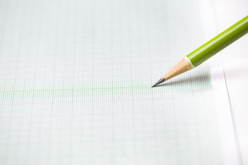 close-up green pencil on graph paper background
