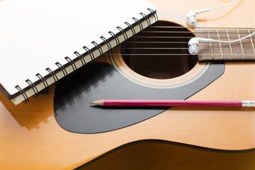 Fototapeta premium Notebook and pencil on guitar
