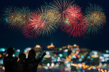 The happy family looks celebration fireworks on the night sky 