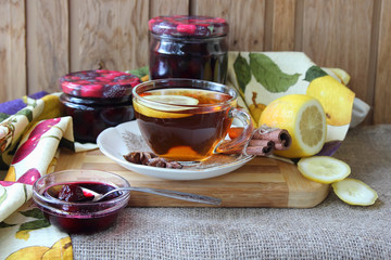 Plate with cherry jam and a cup of tea..