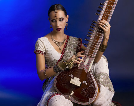 Beautiful Indian Woman in Sari with Oriental Jewelry Playing the