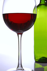 Ein Glas mit Rotwein mit Weinflasche im Hintergrund