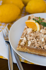 Waffles with meringue, lemon curls and orange slices 