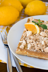 Waffles with meringue, lemon curls and orange slices 