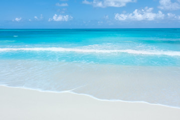 Fototapeta na wymiar Turquoise waters and gentle waves on a white sand Caribbean beach.