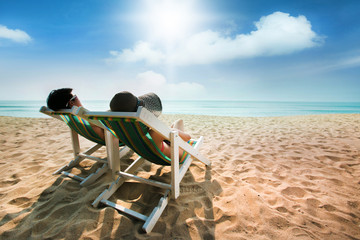 Couple sunbathing on a beach chair The beach is bright blue. Dur