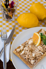 Waffles with meringue, lemon curls and orange slices 