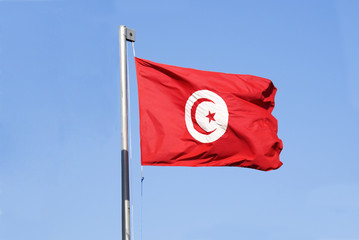 Flag of Tunisia waving on blue sky background