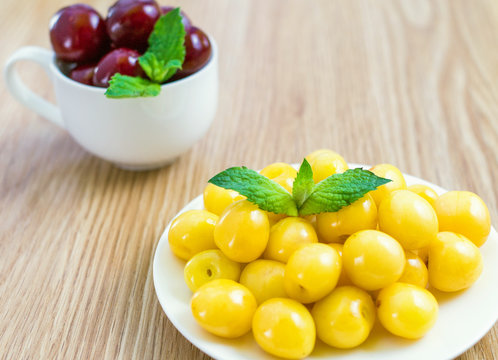 On a table there is a saucer with a yellow sweet cherry.